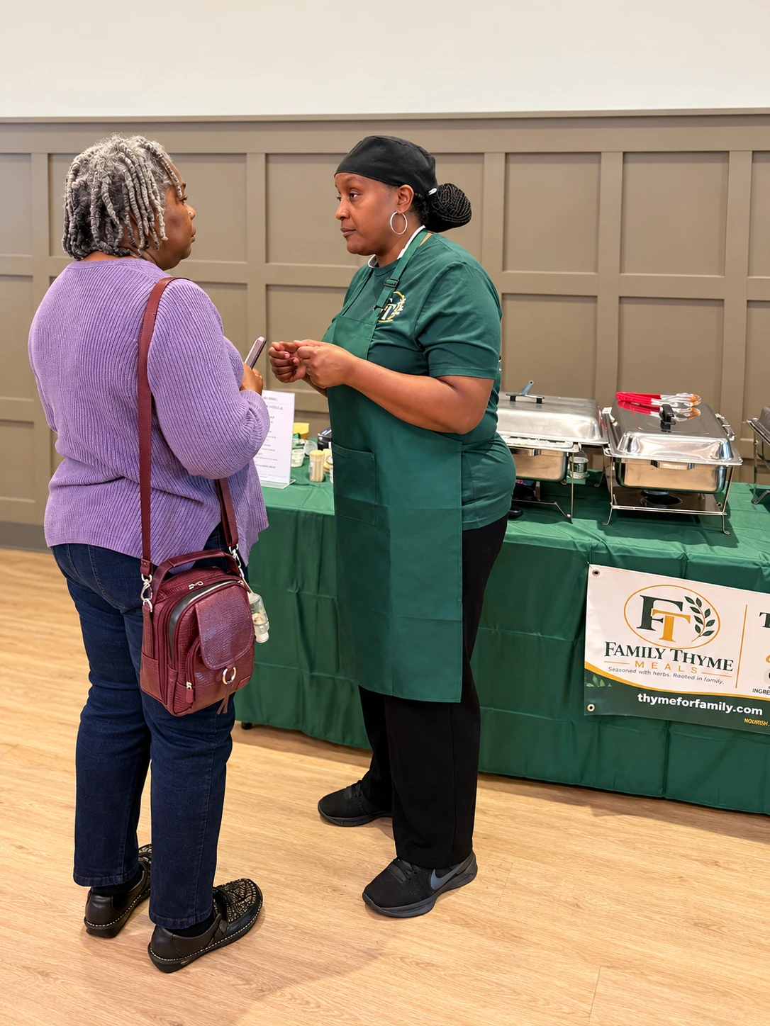 A Family Thyme team member talking with a guest at a community event